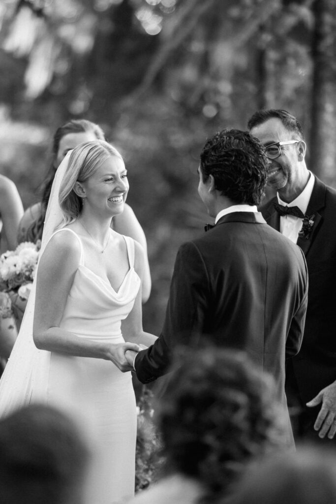 black and white of bride laughing during ceremony