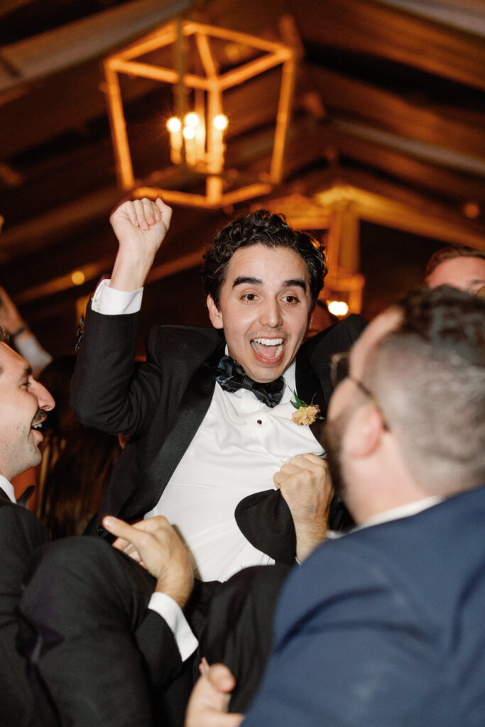 groom getting picked up and tossed by groomsmen