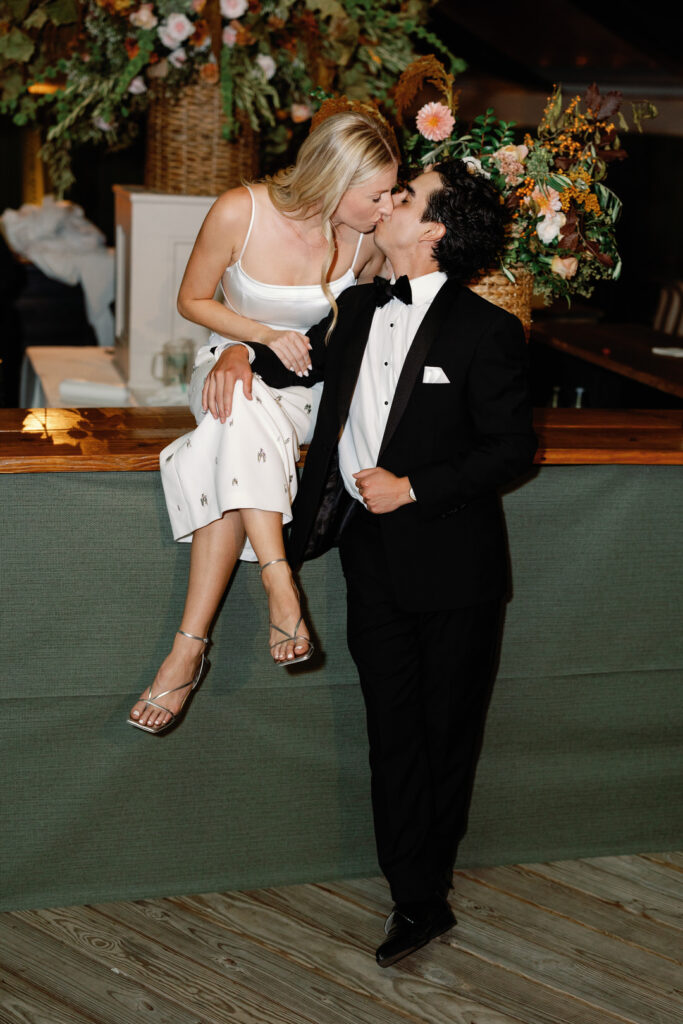 bride sitting on bar kissing groom