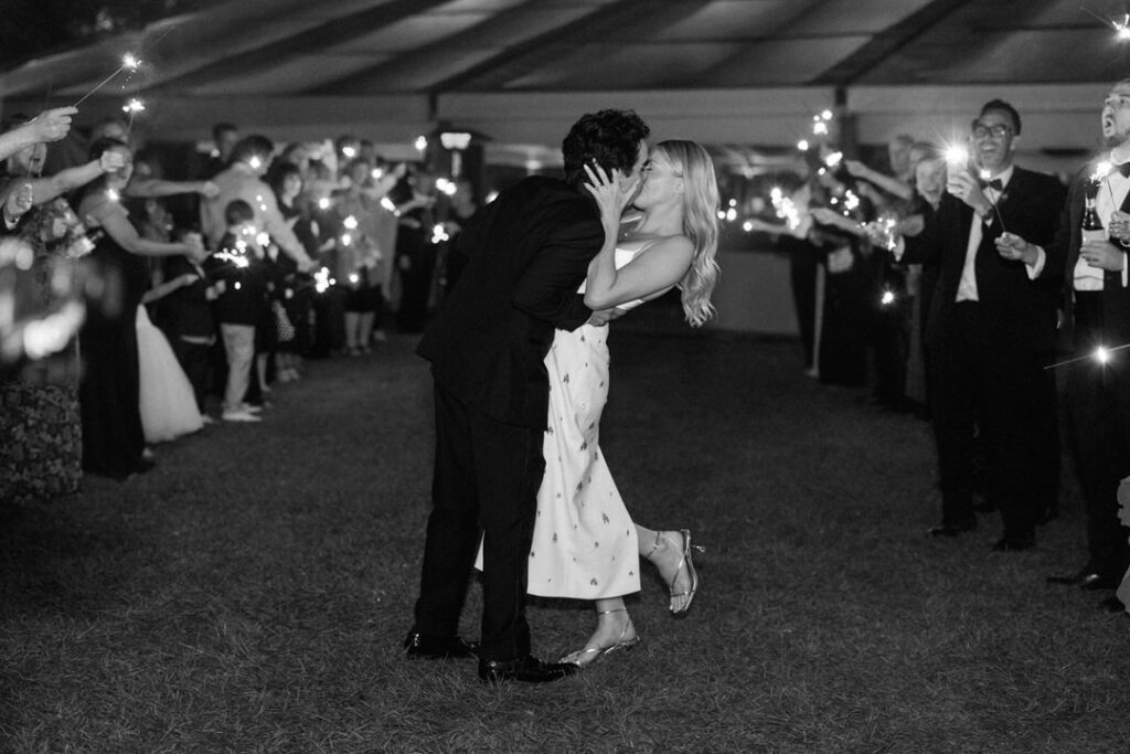 black and white of bride and groom kissing during sparkler exit