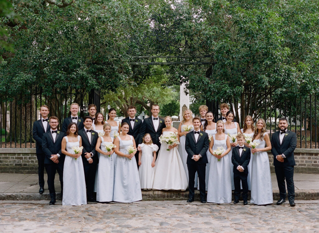 Bride and Groom with Wedding party on cobble stone sidewalk on Chalmers street in Charleston