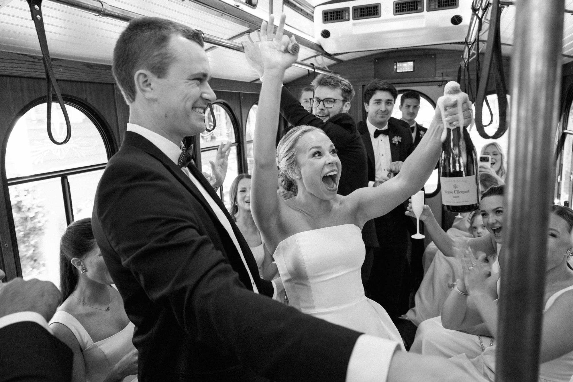 bride and groom celebrating popping champagne on Charleston Trolly on their way to their reception