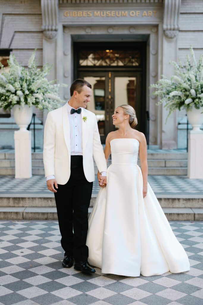 Bride and Groom Holding hands smiling at each other in front of the Gibbes Museum of Art