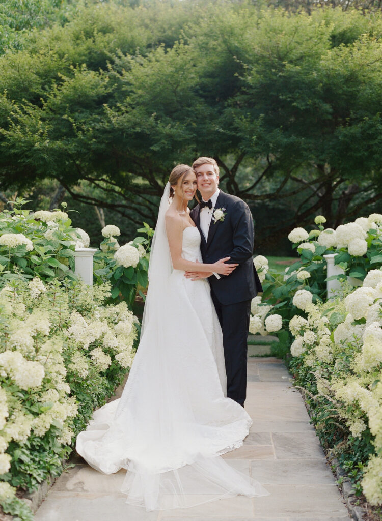 Bride and groom in the orchard at Old Edwards Inn surrounded by hydrangeas 